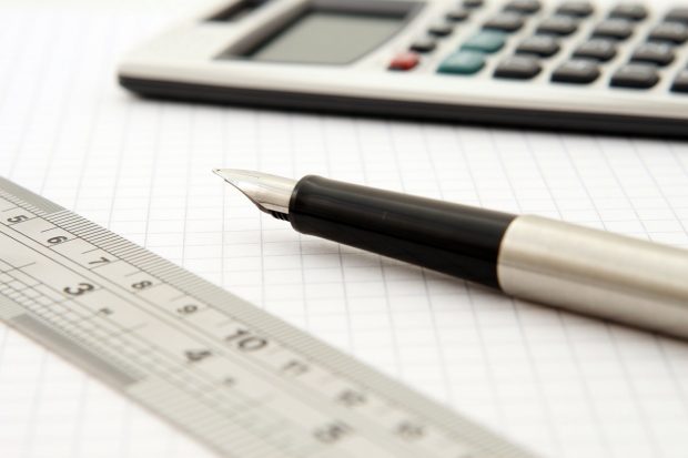 Image of fountain pen, calculator and ruler set on squared paper